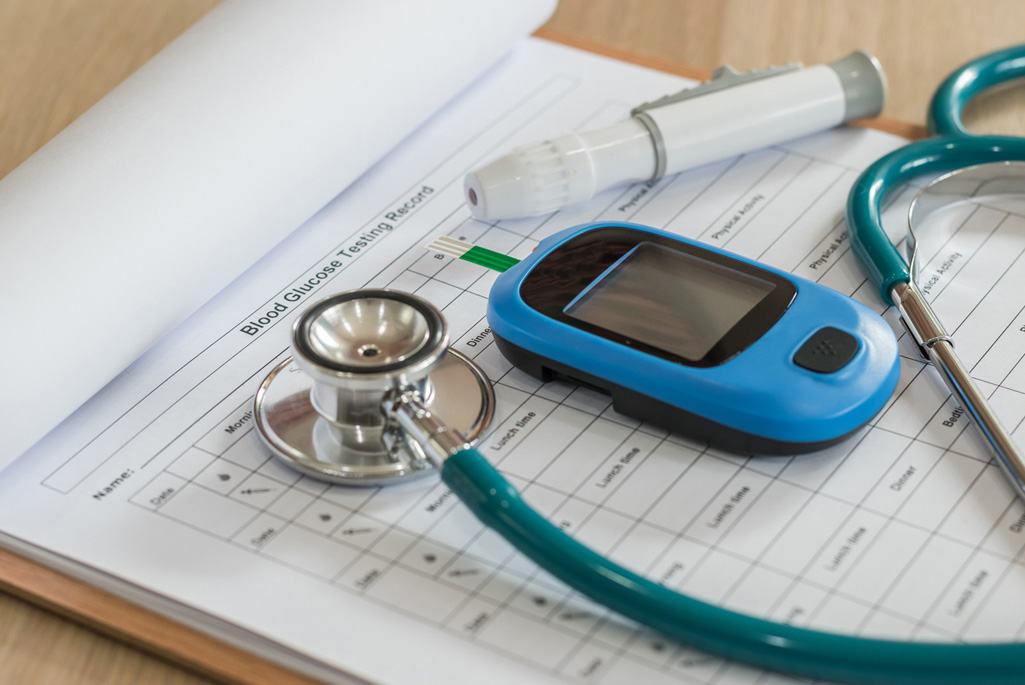 Glucose meter and examination tool kit on a blood glucose testing record.