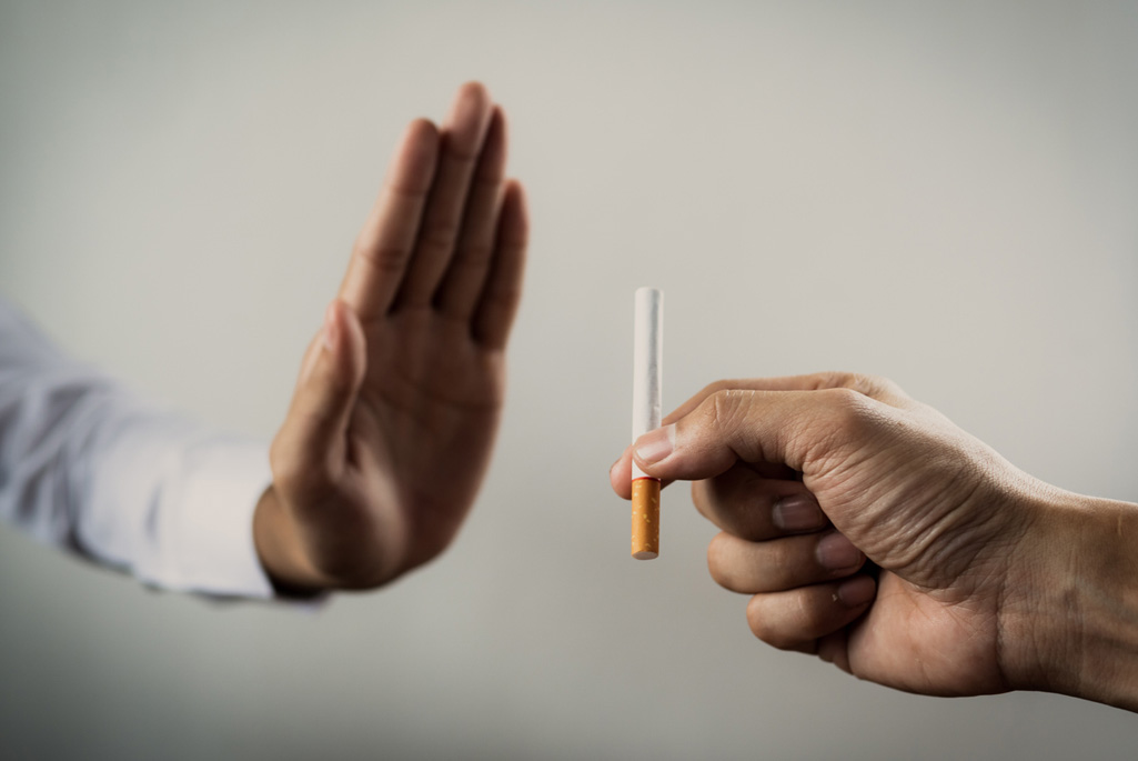 A person's hand gesturing no to an offered cigarette.