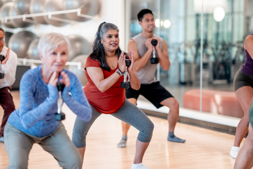 Participants of different backgrounds engage in a weightlifting fitness class at a gym.