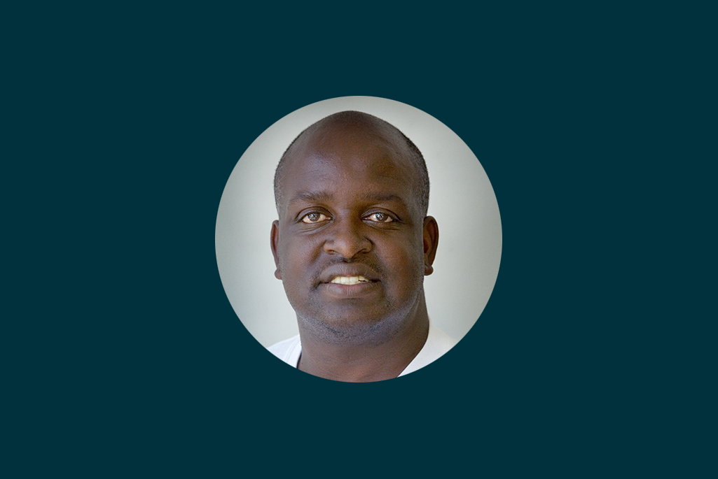 Headshot of person wearing a white tshirt on a dark background