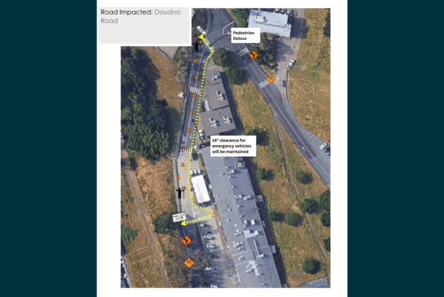 Aerial view of Doudna Road with markings and text indicating retaining wall construction work, flaggers, and pedestrian detours against a navy background.