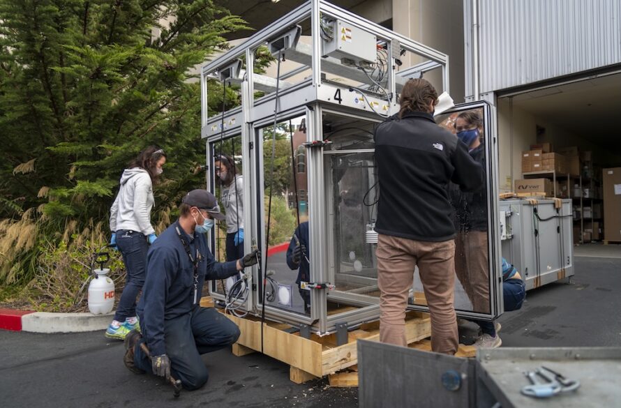 Three members of Berkeley Lab take delivery of a large steel-framed device called an EcoPOD at Potter Street location of of the Lab in Emeryville, California