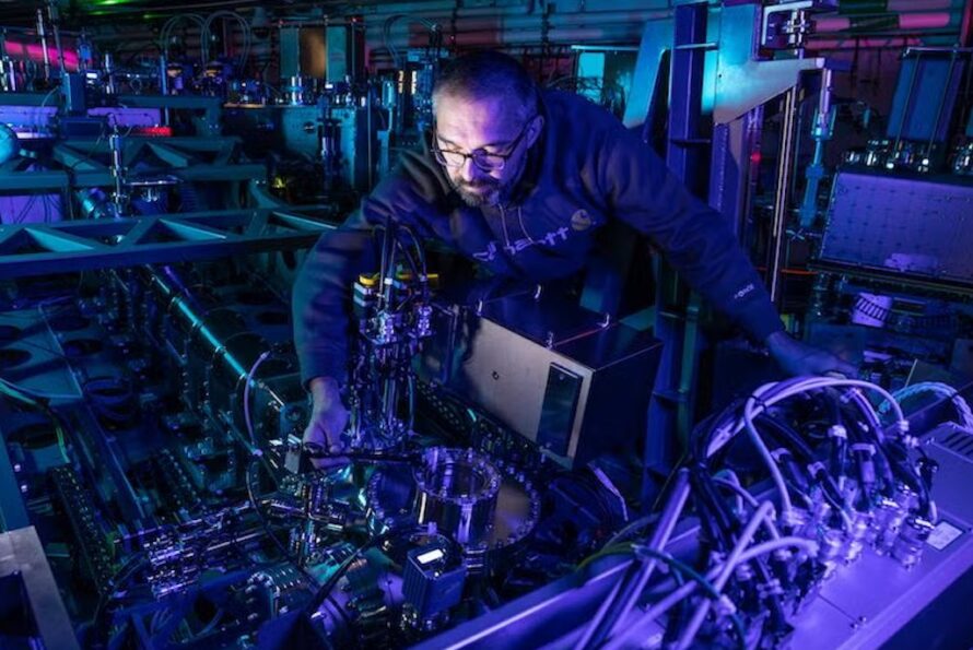 Person in dark lab reaching hand in scientific instrument making adjustments