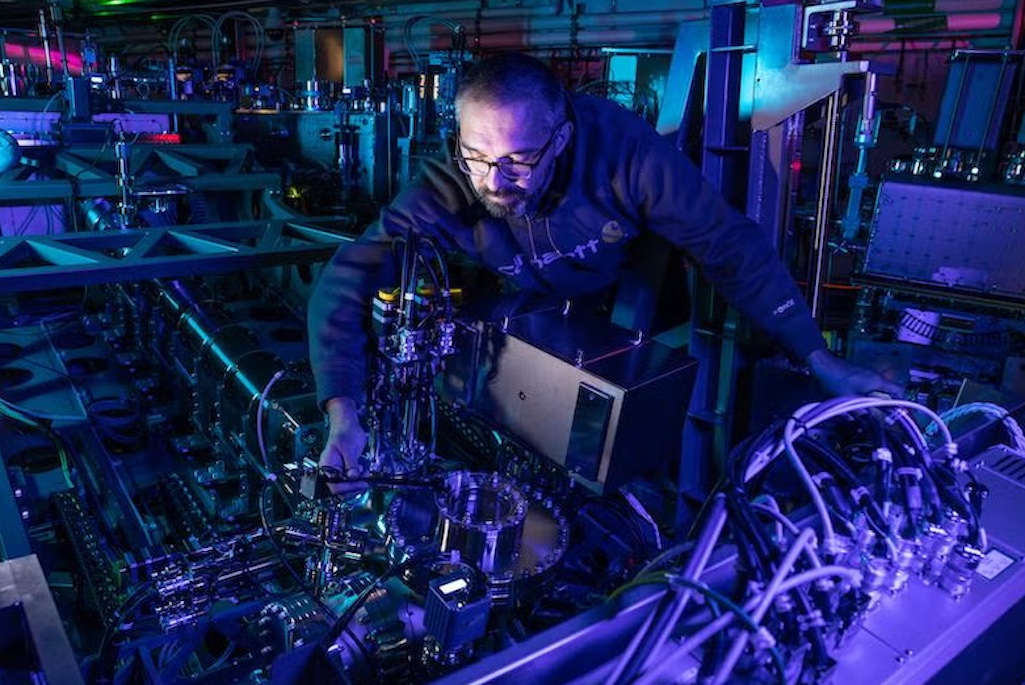 Person in dark lab reaching hand in scientific instrument making adjustments