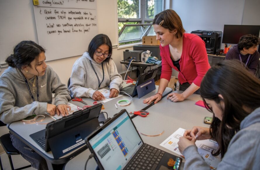 Four persons seated at table with laptop computers open and working on documents in front of them