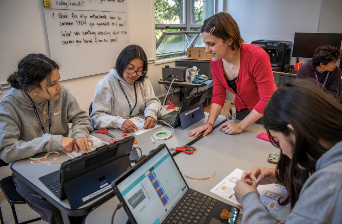 Four persons seated at table with laptop computers open and working on documents in front of them