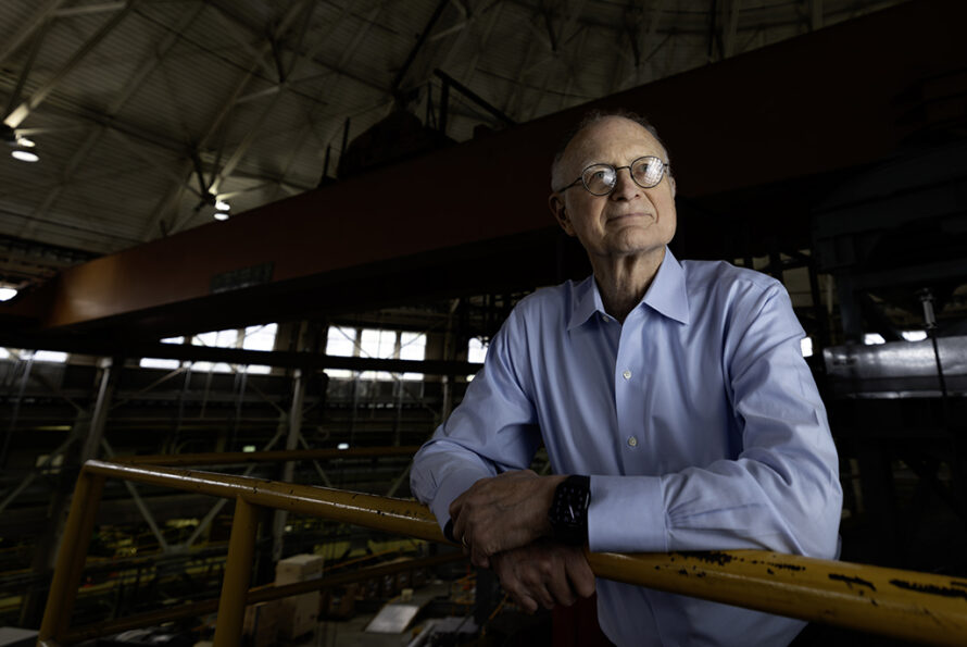 Person wearing glasses and blue shirt against dark background looking out