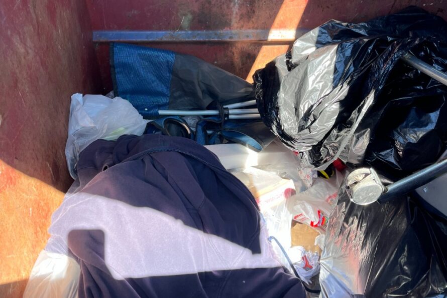 Discarded items including a camping chair, in a waste bin.
