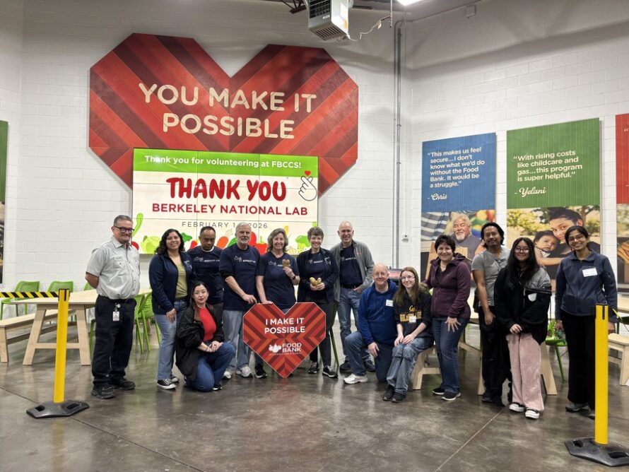 Group of persons standing in front of red, heart-shaped poster with words "You Make It Possible" and a white banner with words "Thank You Berkeley National Lab"