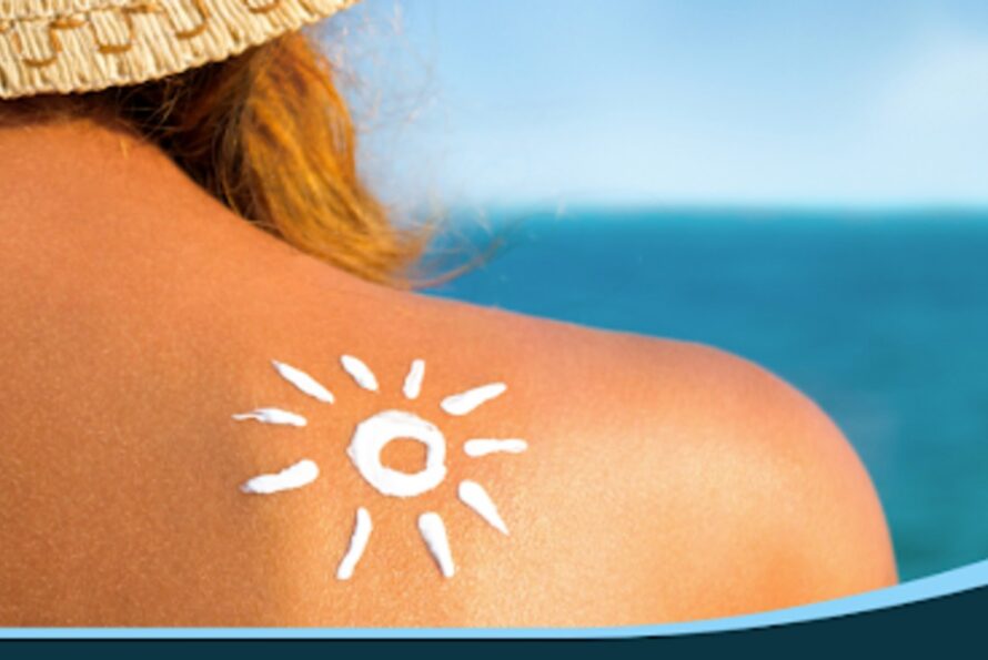 A person at the beach with sunscreen in the shape of a sun on their shoulder.