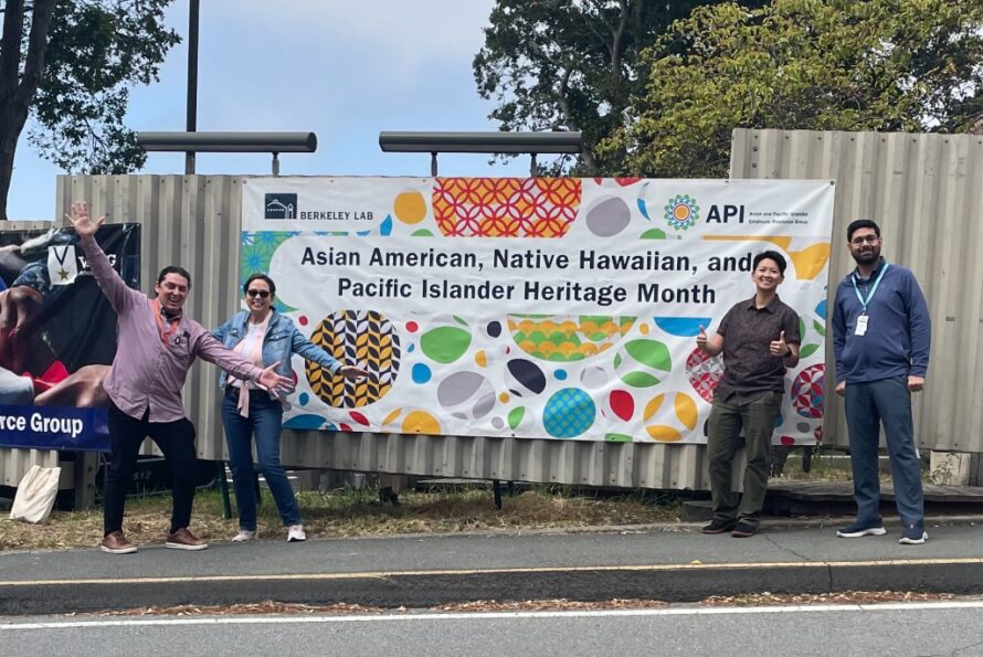 Four persons standing in front of large mounted banner reading "Asian American, Native Hawaiian, and Pacific Islander Heritage Month"