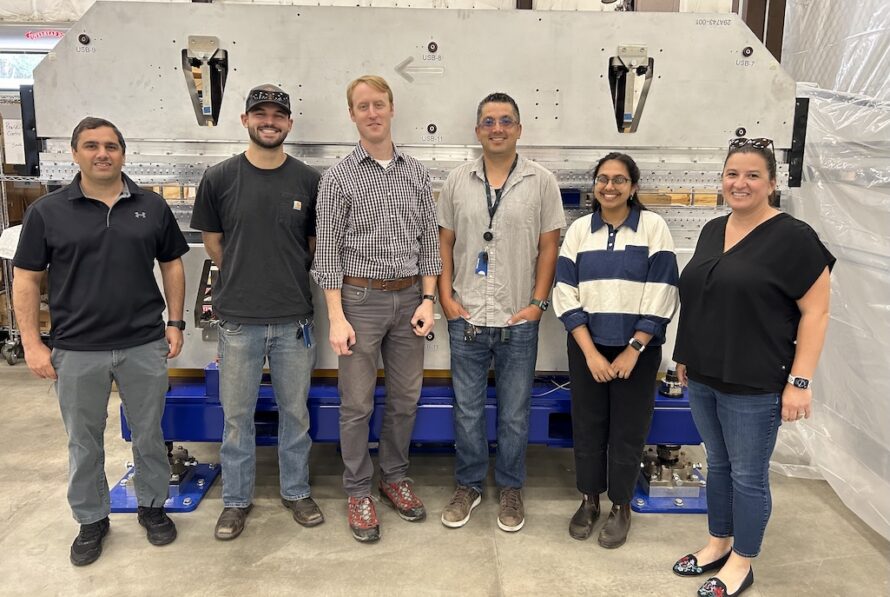 A row of six persons standing in front of a large metal soft x-ray device