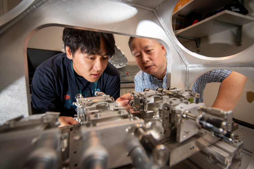 Two people in scientific setting examining circuitry.