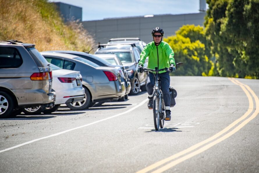 Person wearing a helmet riding a bike down a Lab road.