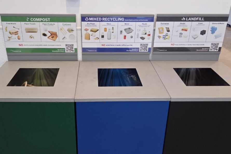 Three recycle bins adjacent to one another: a green bin is labeled "Compost"; a blue bin is labeled "Mixed Recycle"; and a black one is labeled "Landfill"