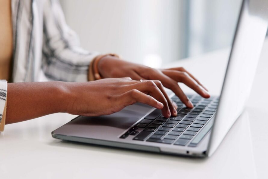 image of a person's hands typing on a laptop keyboard.