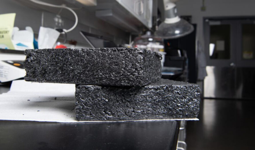 Two stacked samples of rectangular dark gray graphite samples resting on a table.