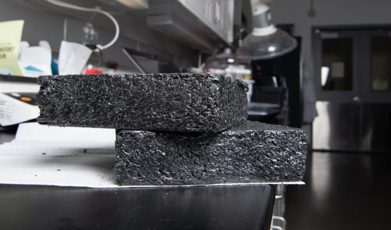 Two stacked samples of rectangular dark gray graphite samples resting on a table.