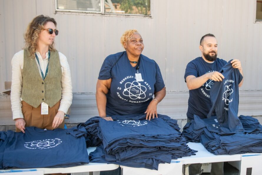 Three volunteers shown at the Runaround handing out t-shirts
