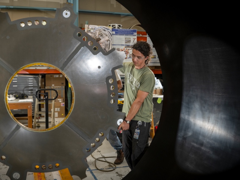 Member of the ATLAS group at Berkeley Lab standing beside an ATLAS ITk Outer Cylinder.