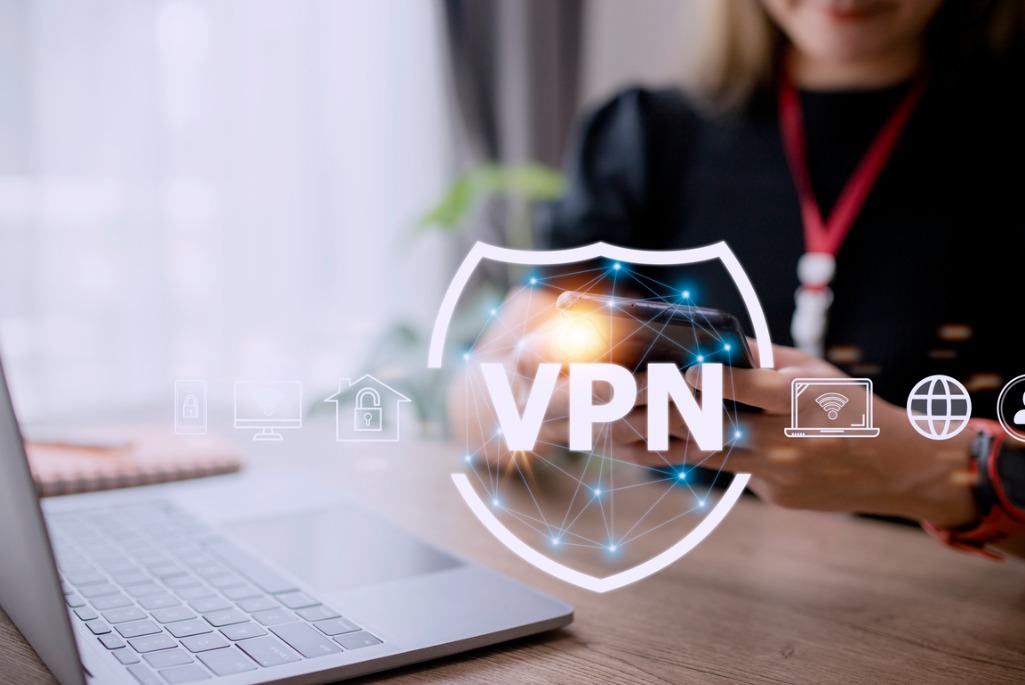 Shield-shaped logo labeled "VPN" overlaid on background of person sitting in front of laptop computer