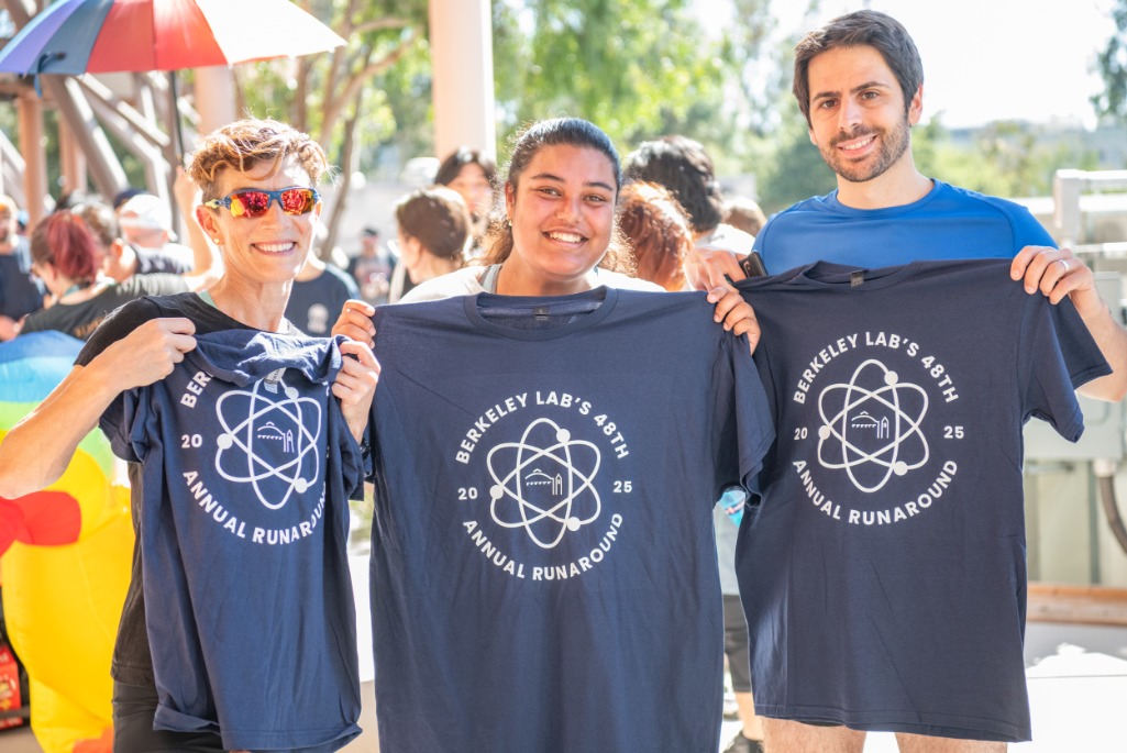 three people in running clothes hold up Runaround-branded t-shirts