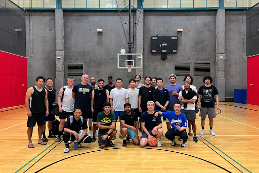 Berkeley Lab basketball team members posing for photo on basketball court with first row of five persons sitting and second row of 17 persons standing.