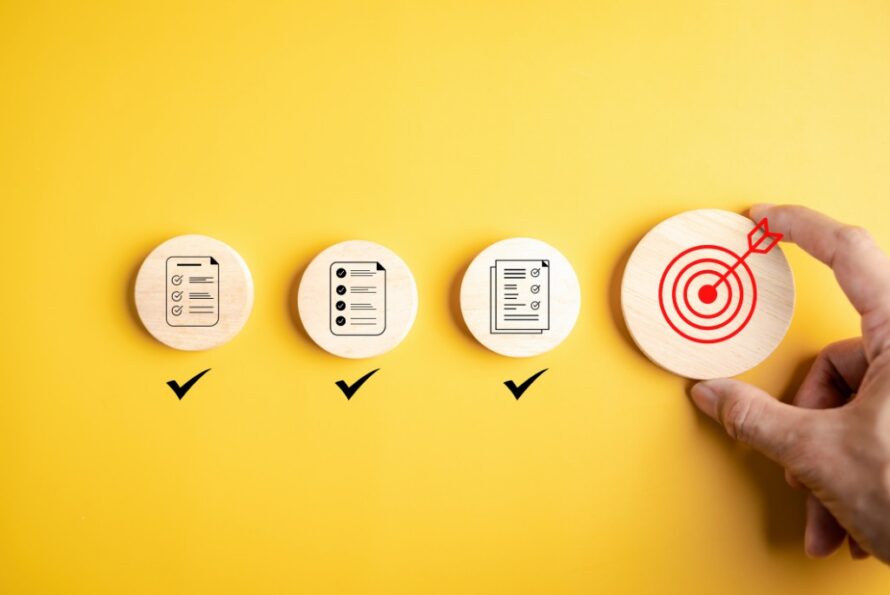 stock image of a hand placing circular blocks representing goals and priorities against a yellow background