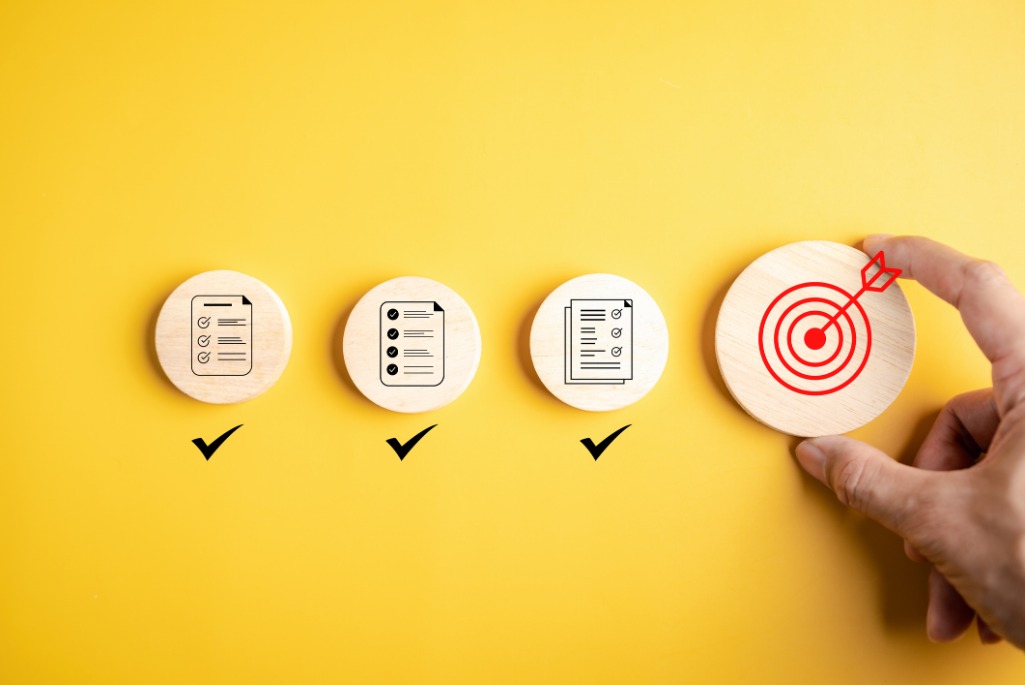 stock image of a hand placing circular blocks representing goals and priorities against a yellow background