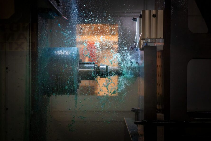 Steel machine tapping into a large steel plate with bright blue shavings emanating from plate.