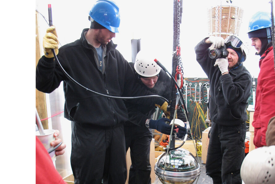 Researchers wearing protective gear with equipment on cable.