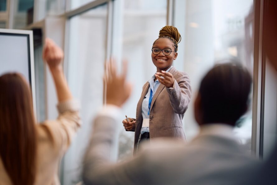 a class with raised hands and an instructor pointing to one participant