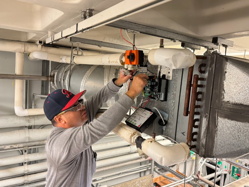 Technician adjusting overhead device with outstretched arms repairing water instrumentation.